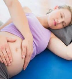 Pregnancy massage pcituredd with specialist therapist with hands on pregnant women's belly for comfort